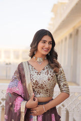 Woman wearing a traditional outfit with a decorative blouse and saree, standing in front of an architectural background.