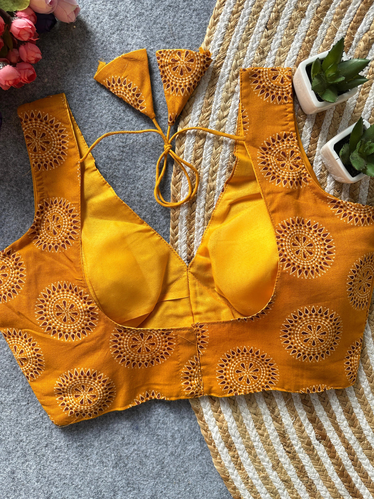 Yellow bikini top with intricate patterns on a textured surface.