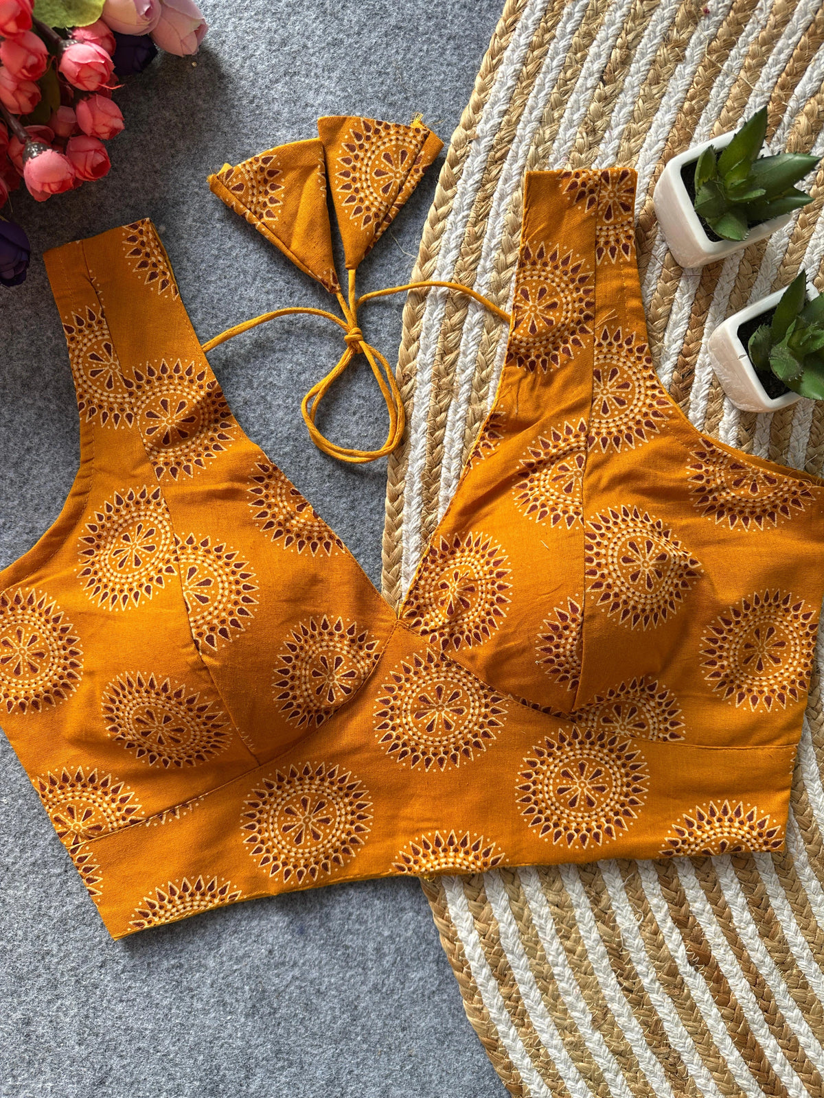 Orange embroidered bikini set on a textured surface with flowers and plants in the background