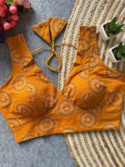 Orange embroidered bikini set on a textured surface with flowers and plants in the background