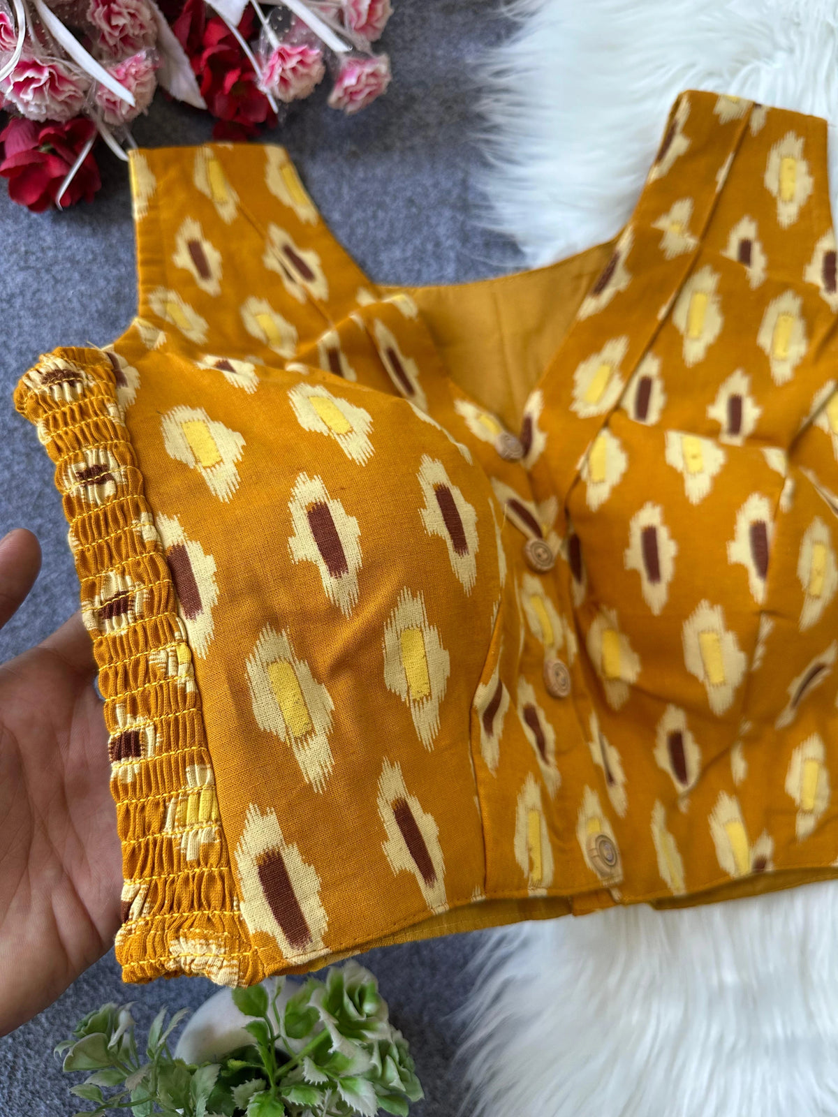 Yellow patterned top with decorative trim on a textured surface