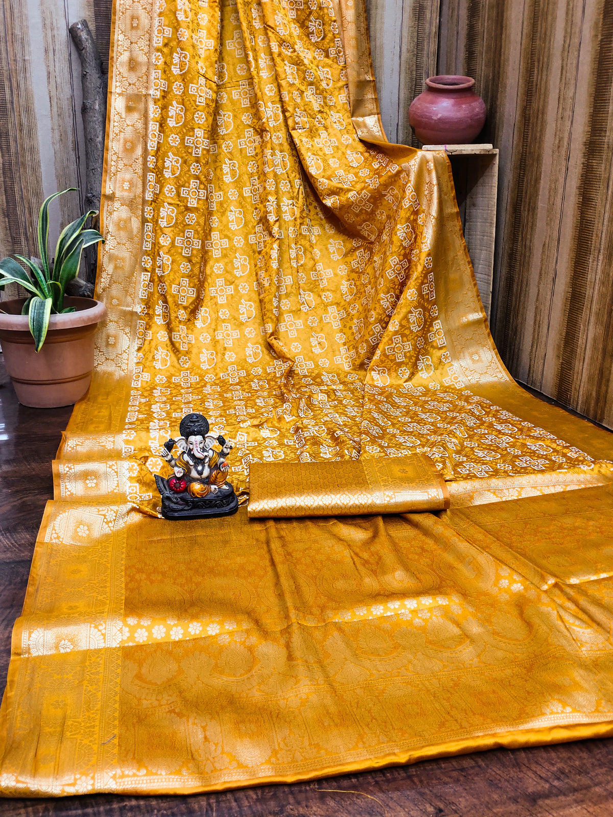 Yellow saree with gold patterns on a wooden floor