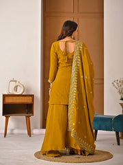 Woman in a yellow traditional outfit with a matching dupatta in a room setting.