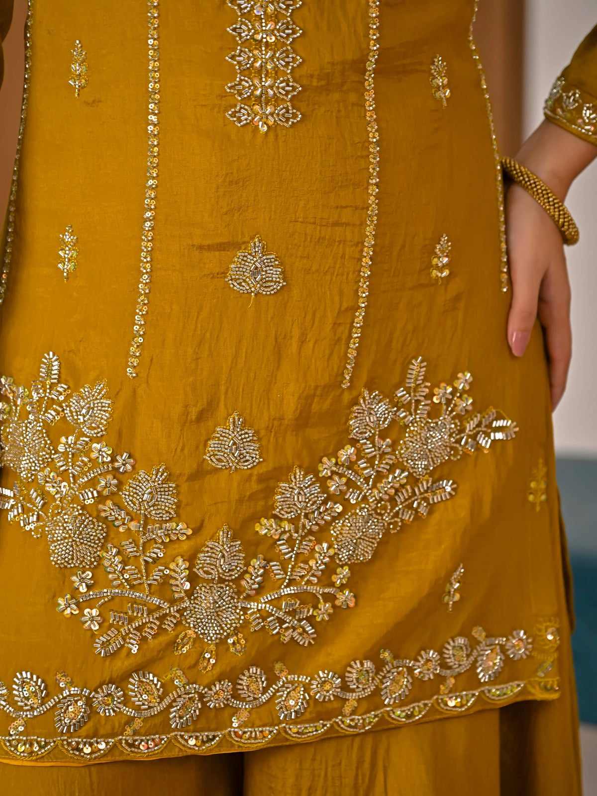 Close-up of a mustard yellow outfit with intricate gold embroidery.