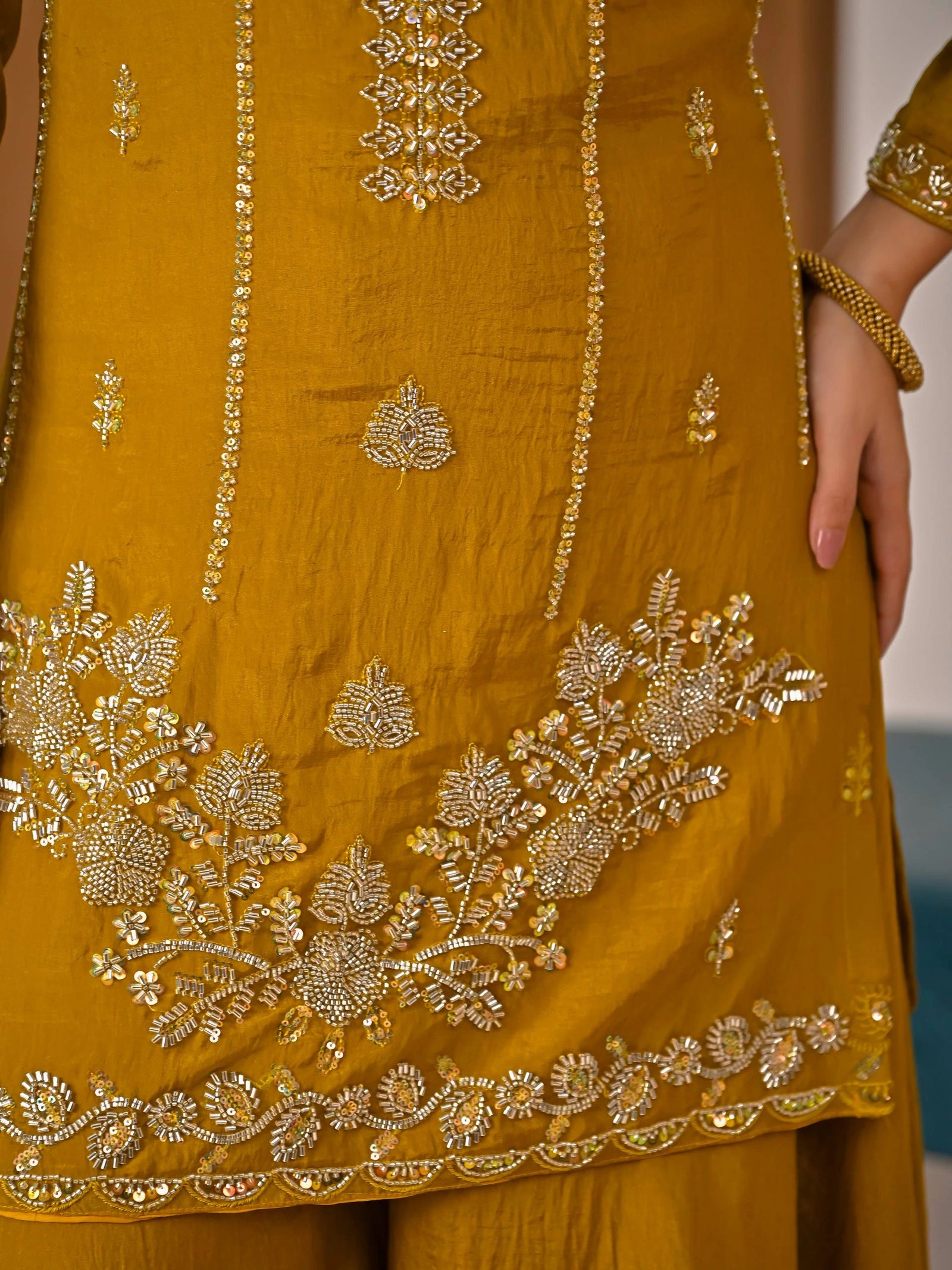Close-up of a mustard yellow outfit with intricate gold embroidery.