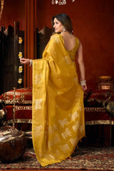 Woman in a yellow saree with white patterns in an ornate setting