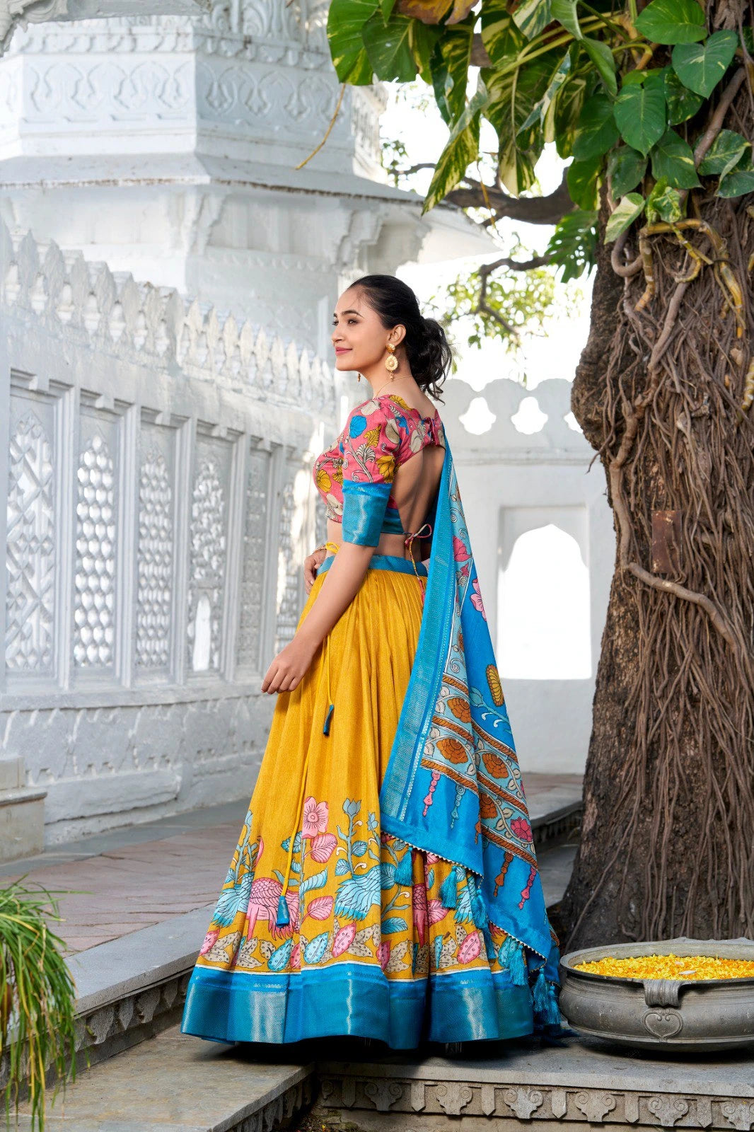 Traditional floral lehenga set in mustard yellow paired with a colorful printed blouse and a rich blue dupatta, creating a festive ethnic look.