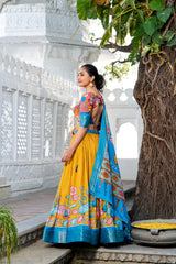Traditional floral lehenga set in mustard yellow paired with a colorful printed blouse and a rich blue dupatta, creating a festive ethnic look.