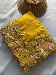 Yellow fabric with intricate embroidery on a gray surface