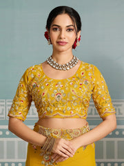 Woman wearing a yellow embroidered blouse with intricate designs against a light gray background