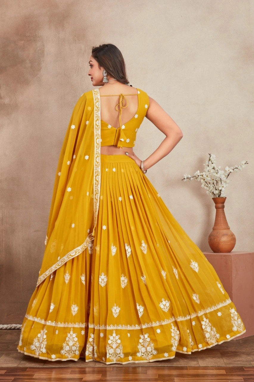 Woman wearing a yellow saree with white patterns against a beige background