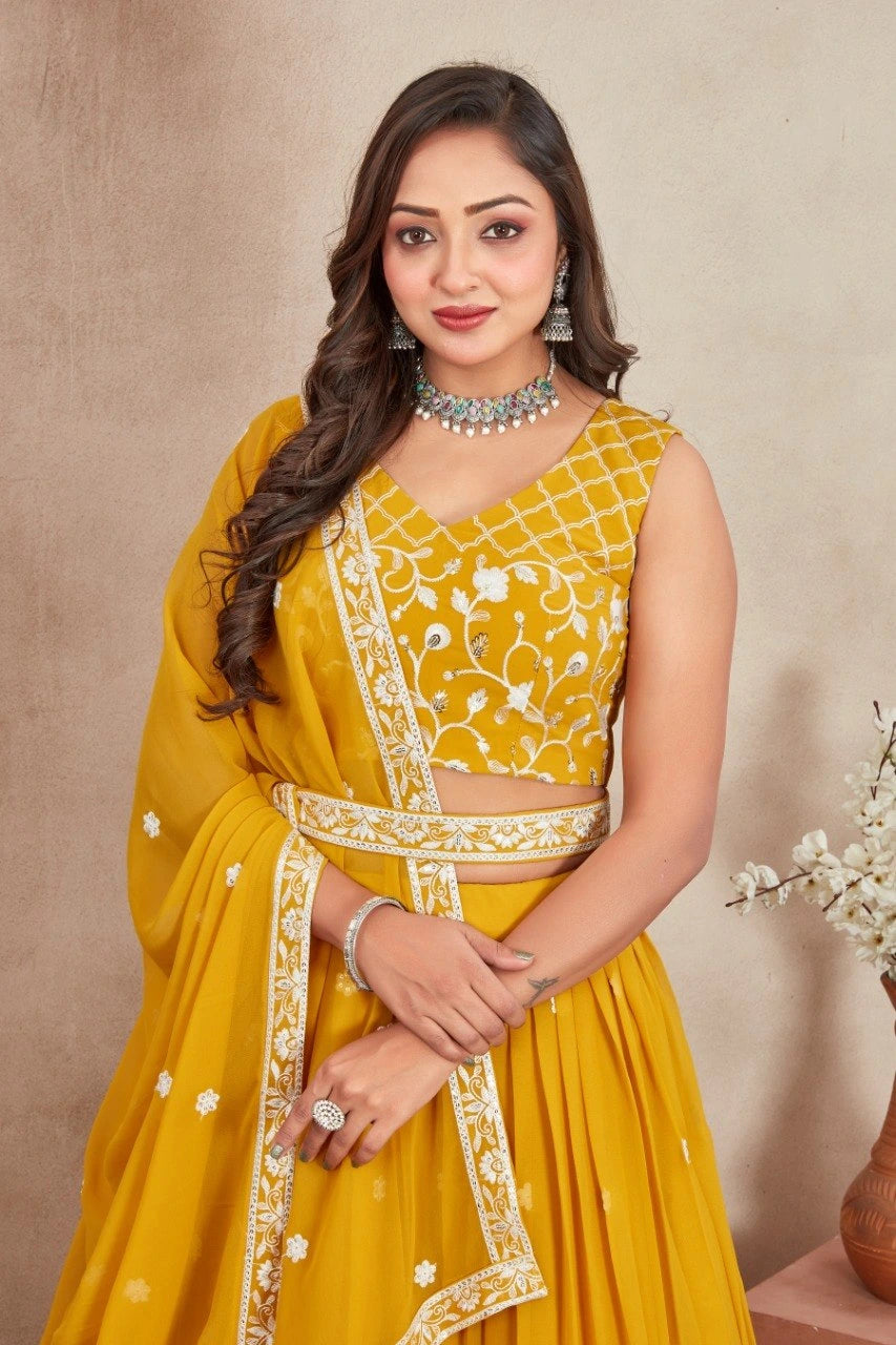 Woman wearing a yellow embroidered outfit with jewelry against a beige background