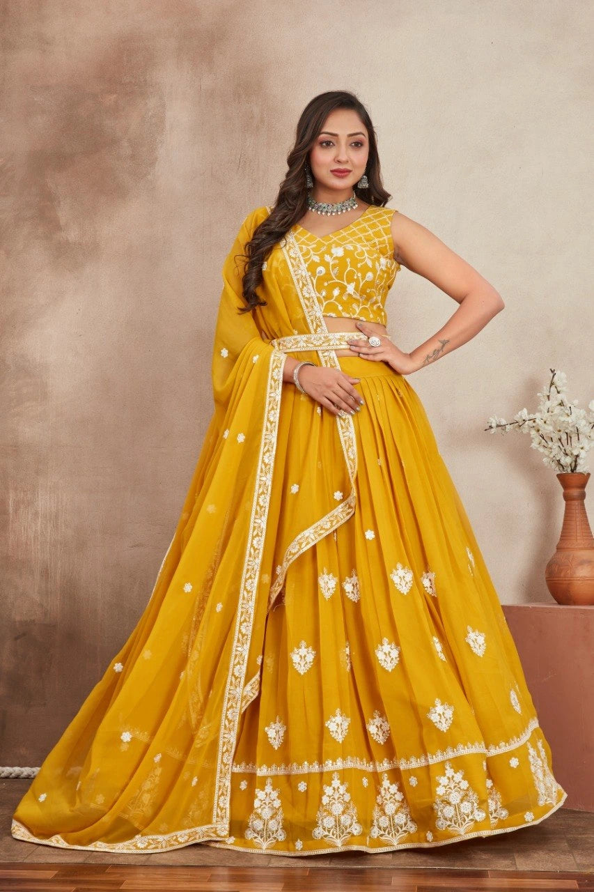 Woman wearing a yellow embroidered saree with a plain background