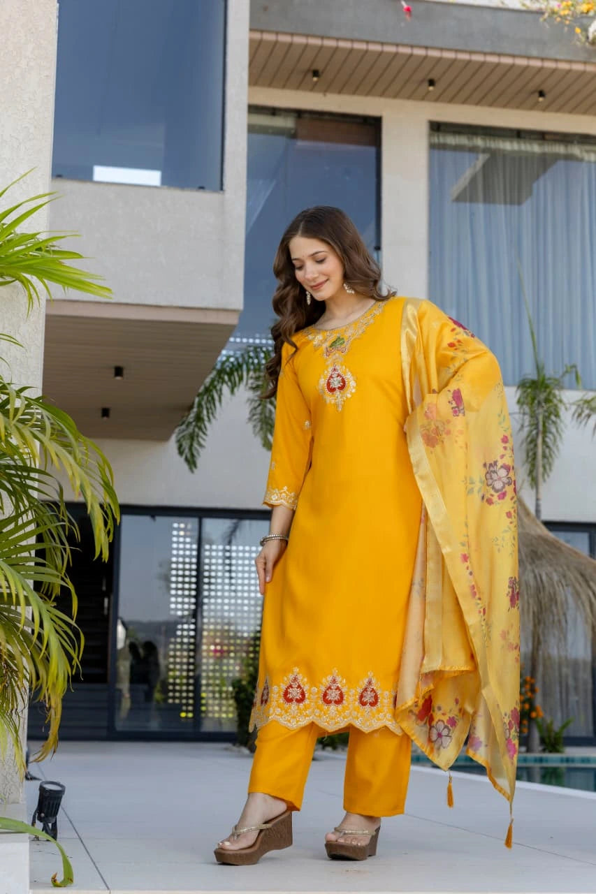 Woman in a yellow traditional outfit standing in front of a modern building.