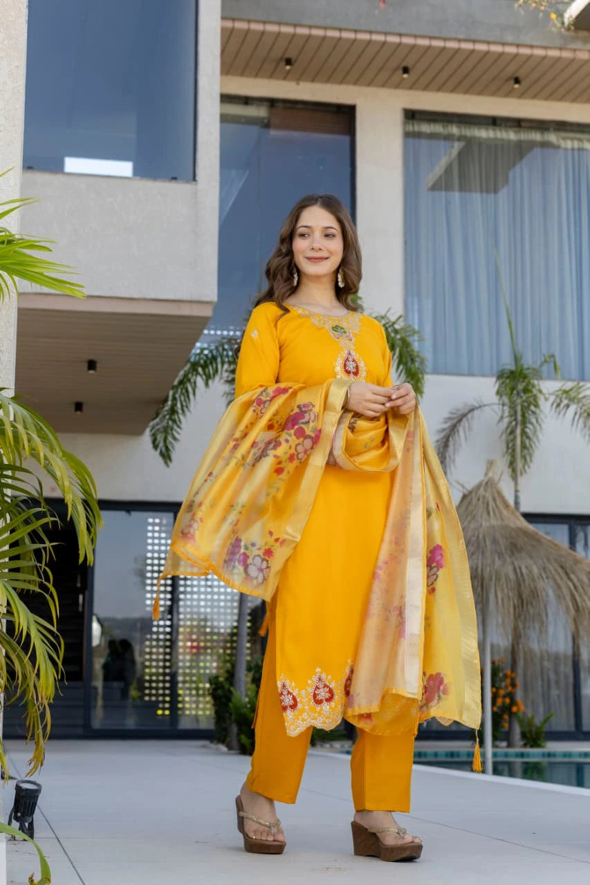 Woman in a yellow traditional outfit standing in front of a modern building.