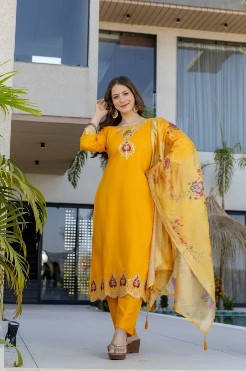 Woman in a yellow traditional outfit standing in front of a modern building.