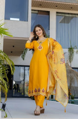 Woman in a yellow traditional outfit standing in front of a modern building.