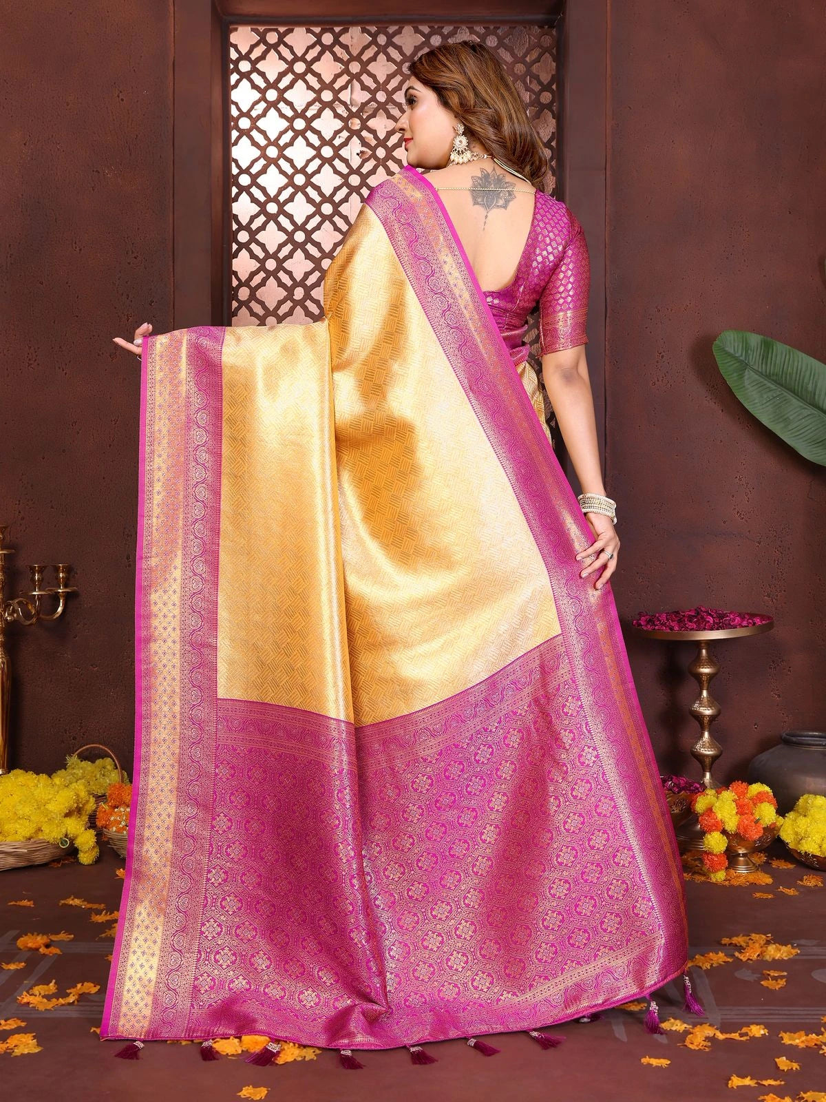Woman wearing a pink saree with gold border in a decorated indoor setting