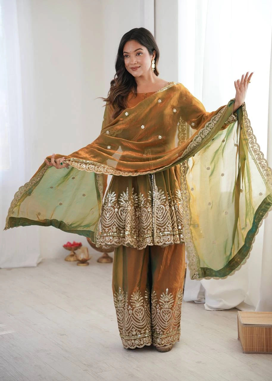 Woman in traditional embroidered outfit with a green dupatta in a bright room.