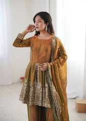 Woman wearing a traditional outfit with intricate designs in a bright room.