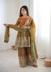Woman wearing a traditional outfit with intricate patterns in a bright room.