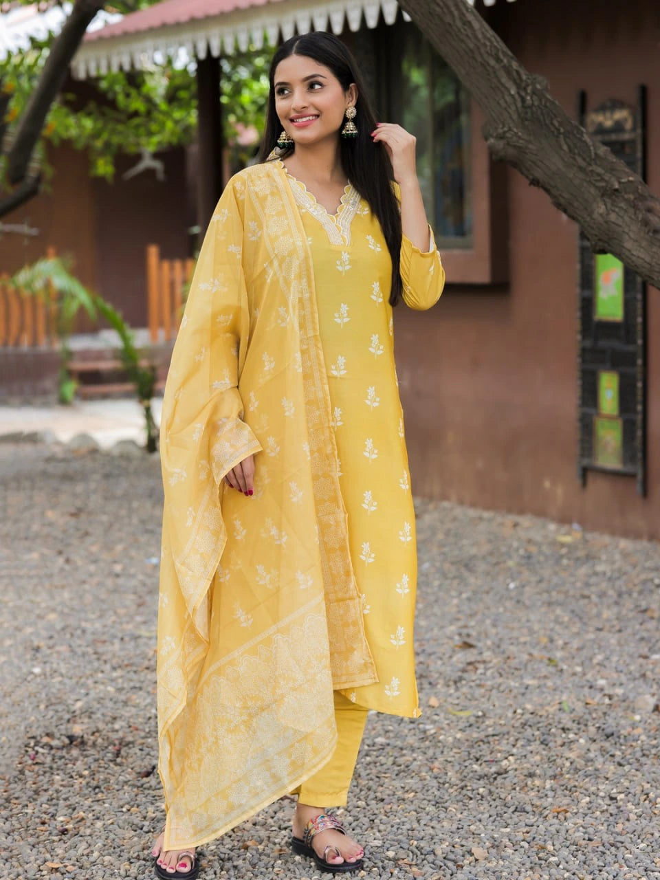 Woman wearing a yellow traditional outfit standing outdoors.