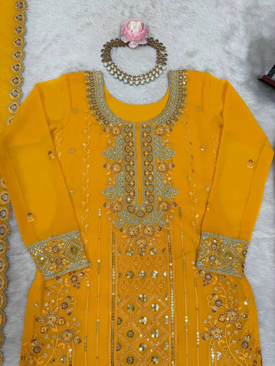 Yellow embroidered dress with intricate patterns on a light gray background
