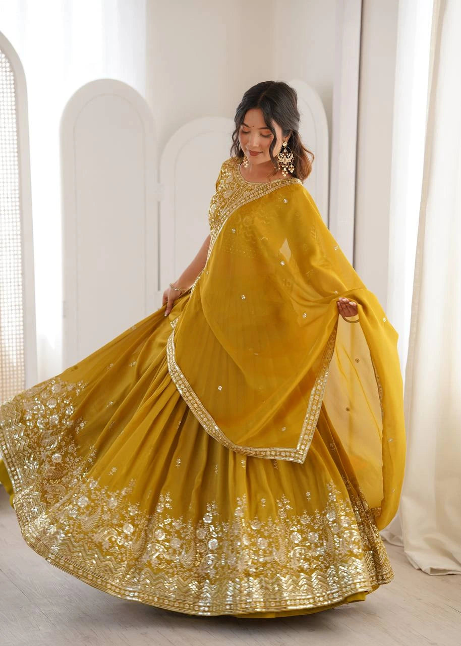 Woman in a yellow traditional outfit with gold embroidery against a white curtain background
