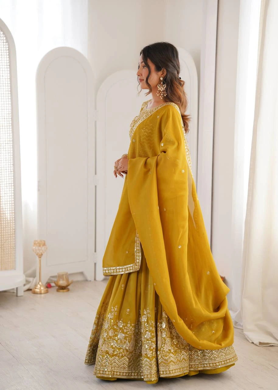 Woman in a yellow traditional outfit with embroidery standing in a minimalistic room.