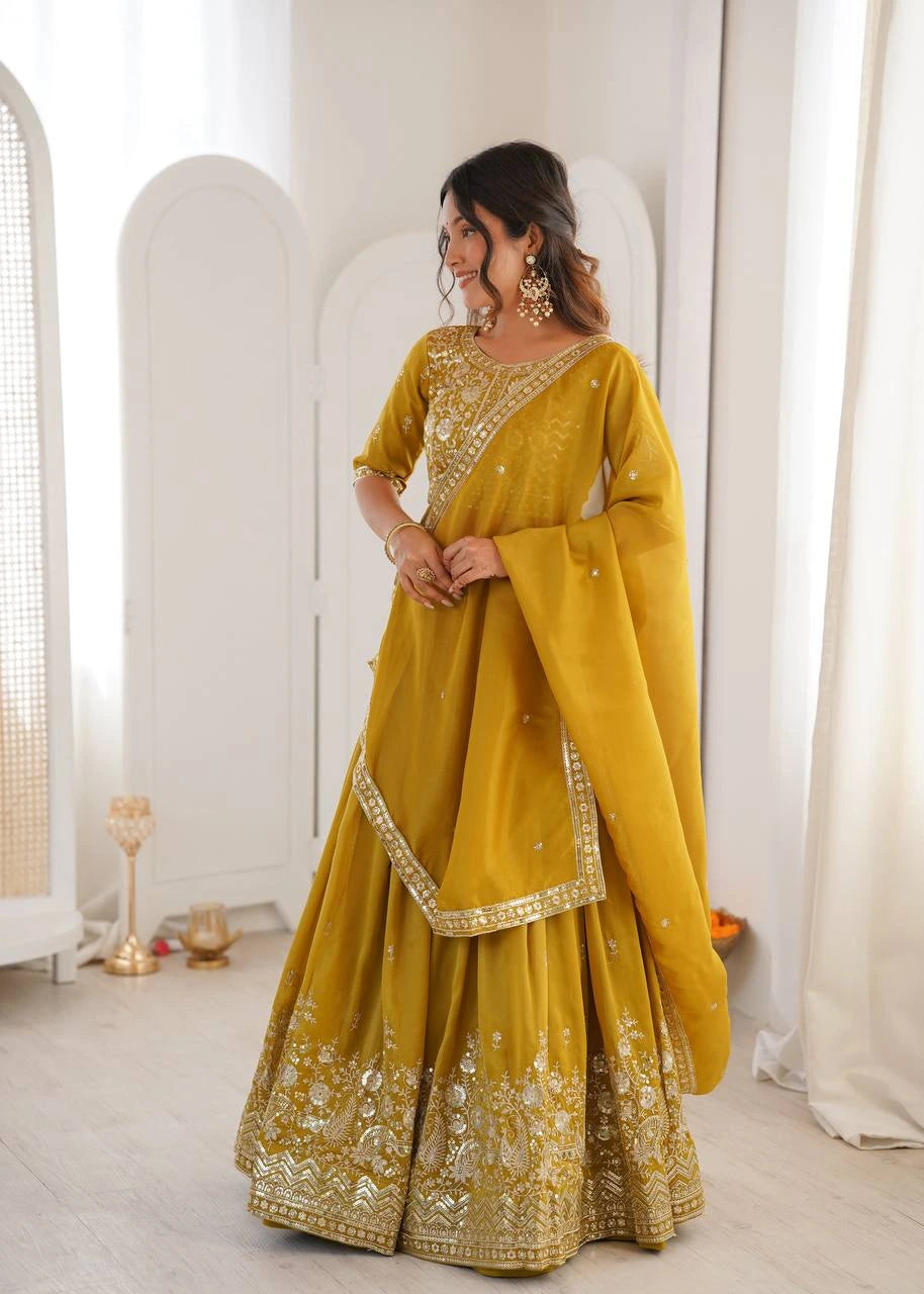 Woman wearing a yellow embroidered traditional outfit in a white room.