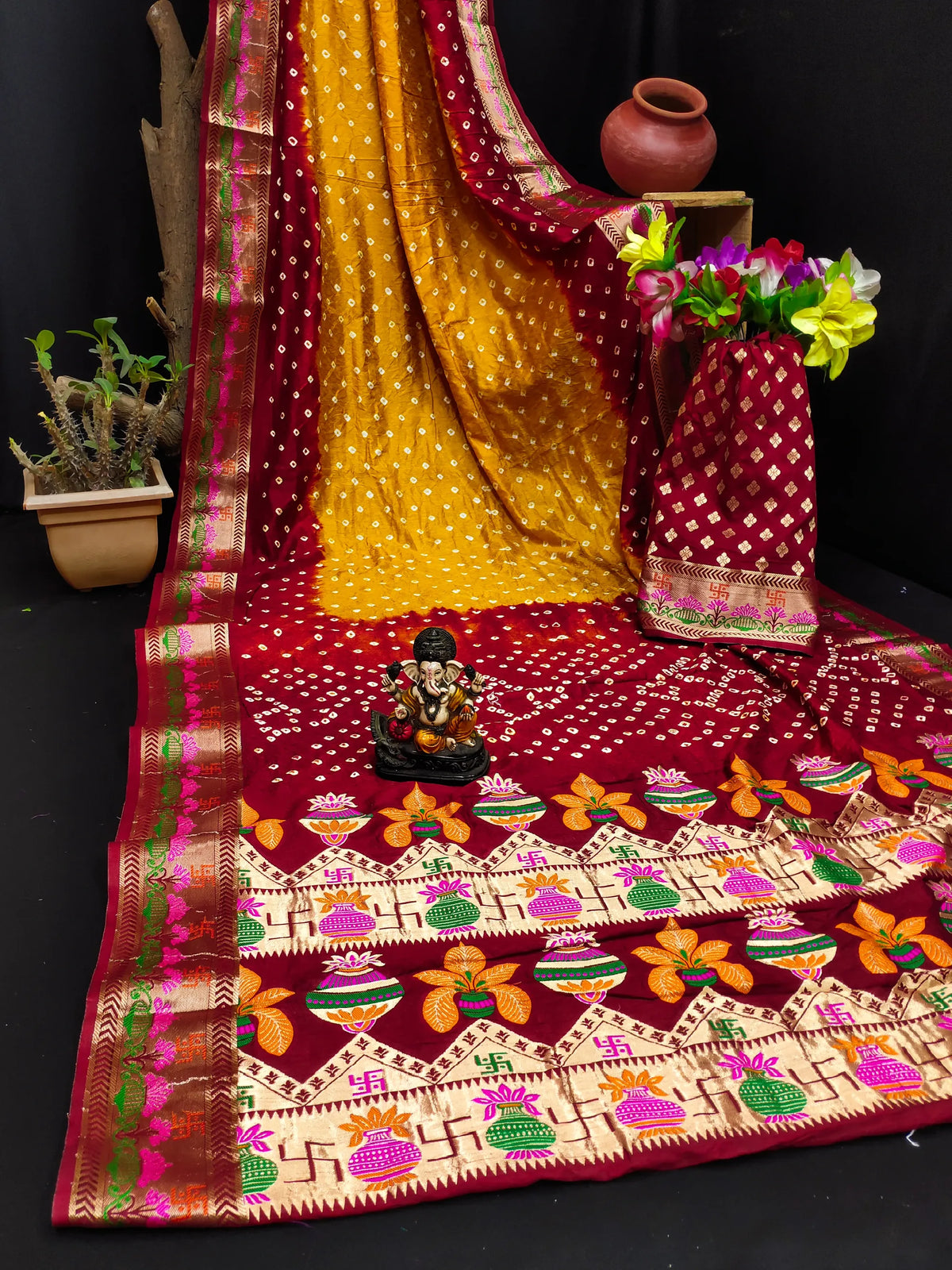 Decorative saree with colorful patterns and a small statue on a black background
