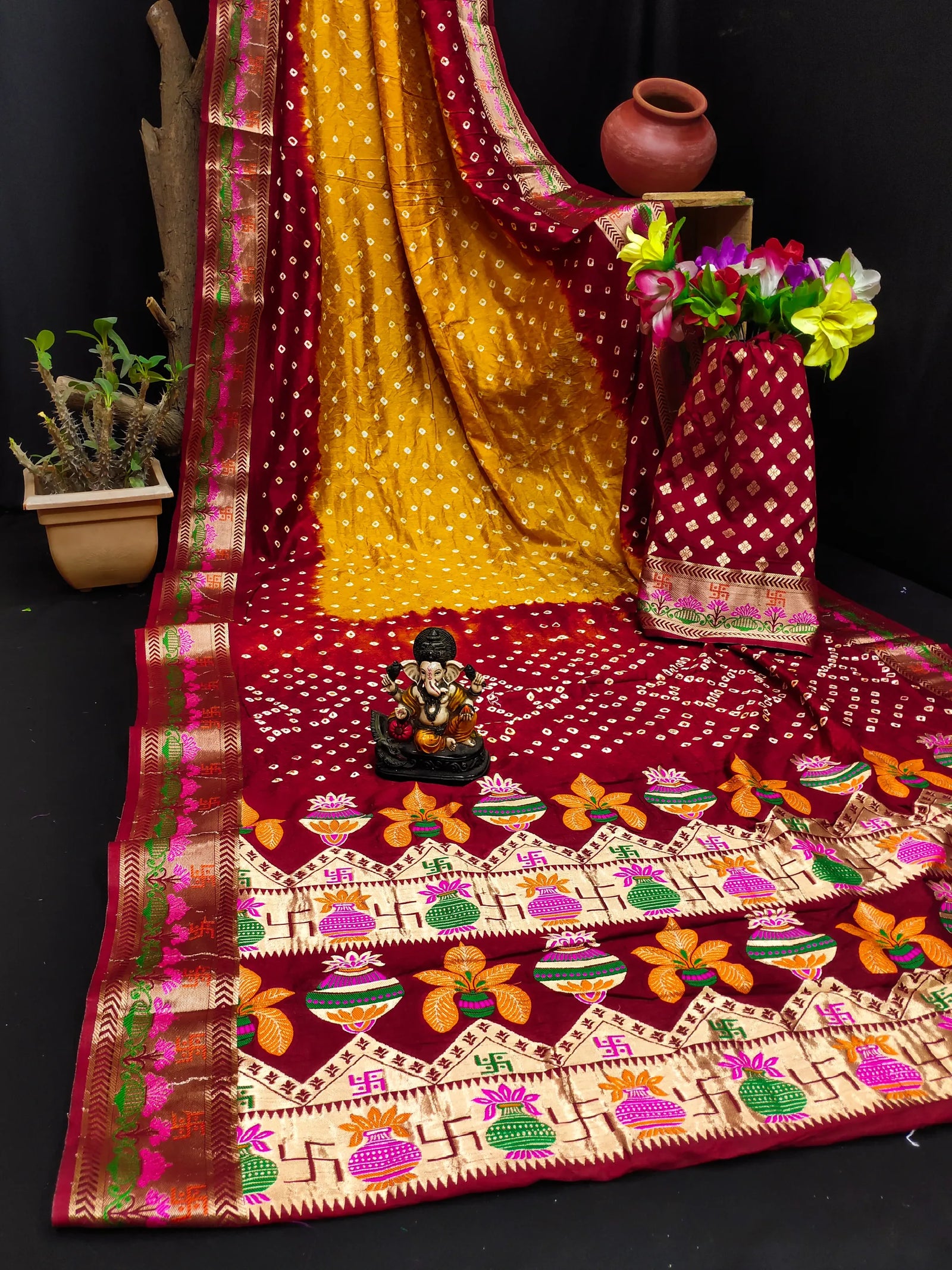 Decorative saree with colorful patterns and a small statue on a black background
