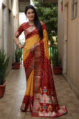 Woman wearing a traditional saree with a red and yellow pattern in an outdoor setting.