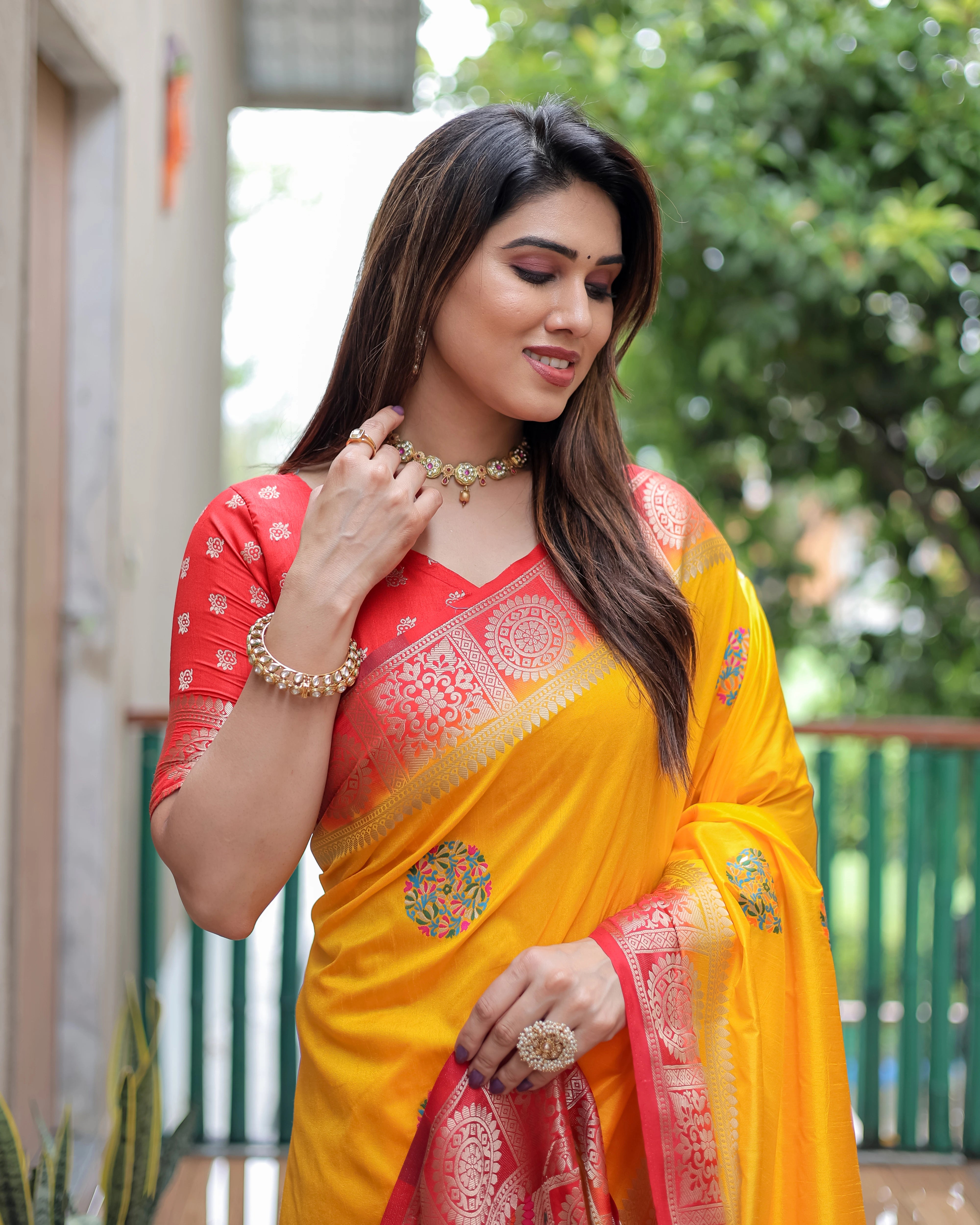 Woman wearing a yellow and red saree with jewelry outdoors