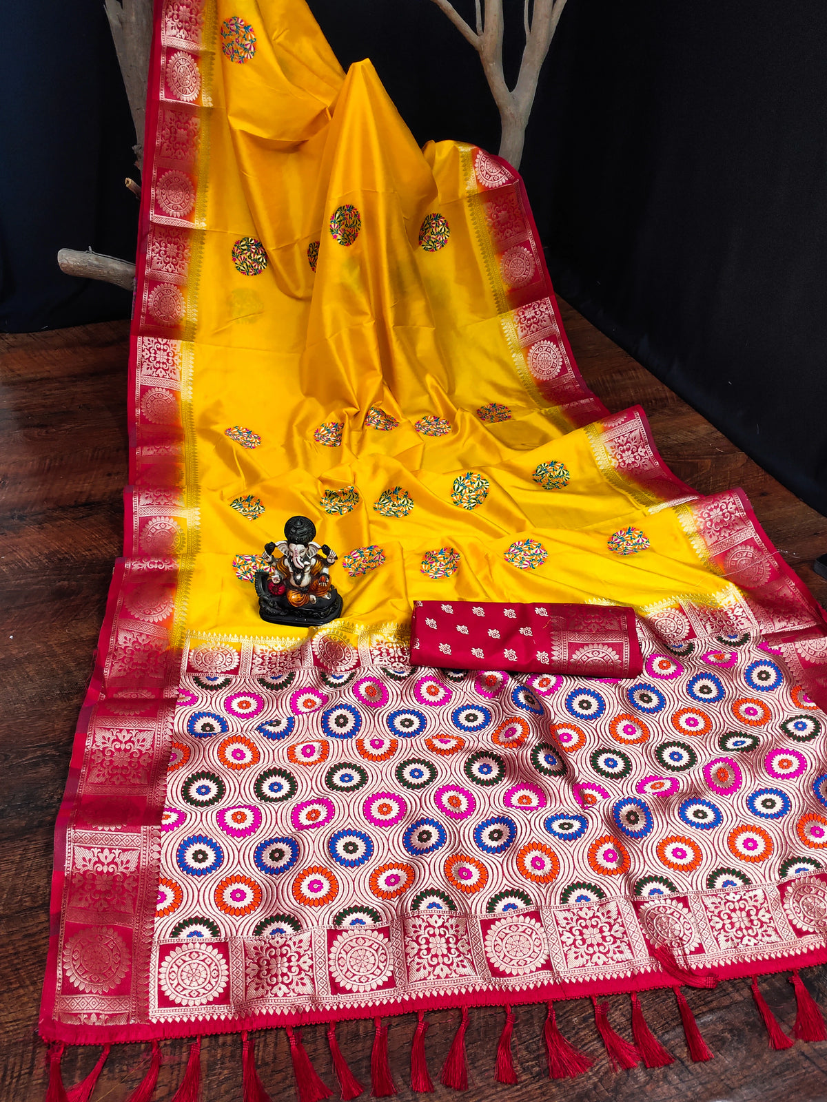 Yellow saree with red and multicolor patterned border on a wooden surface