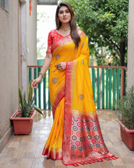 Woman wearing a yellow and red saree with a patterned border, standing on a wooden deck.