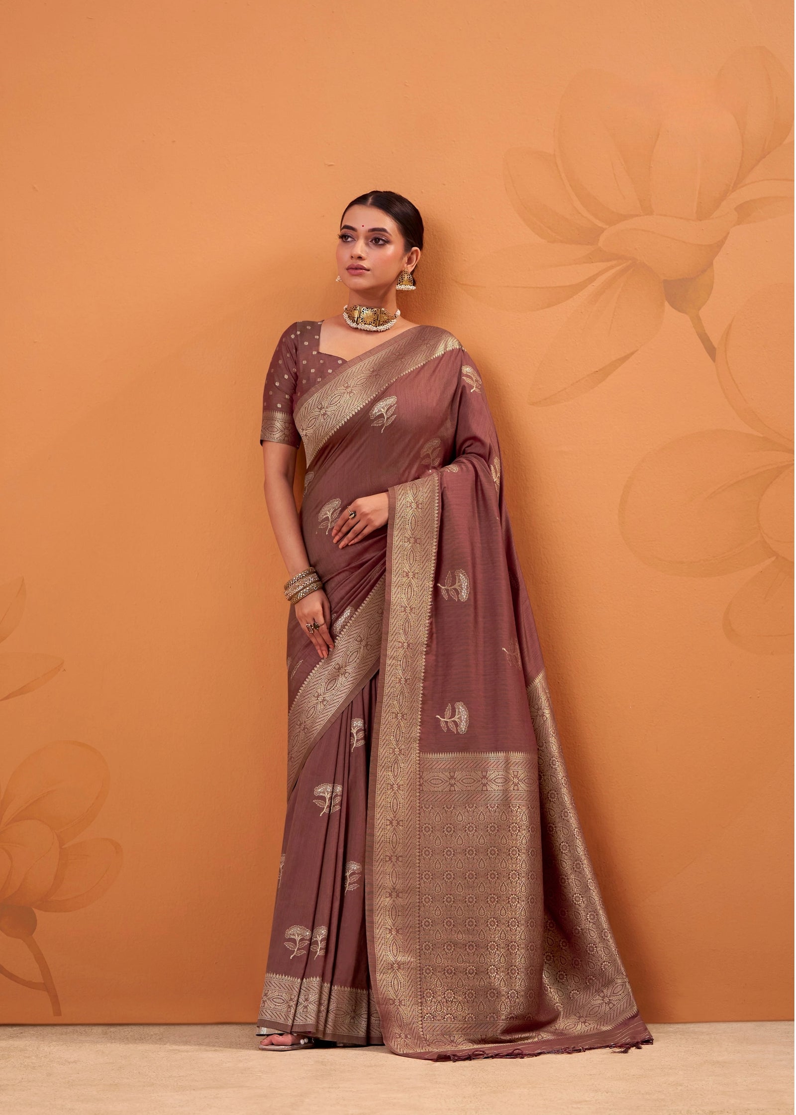 Woman wearing a traditional saree against an orange background
