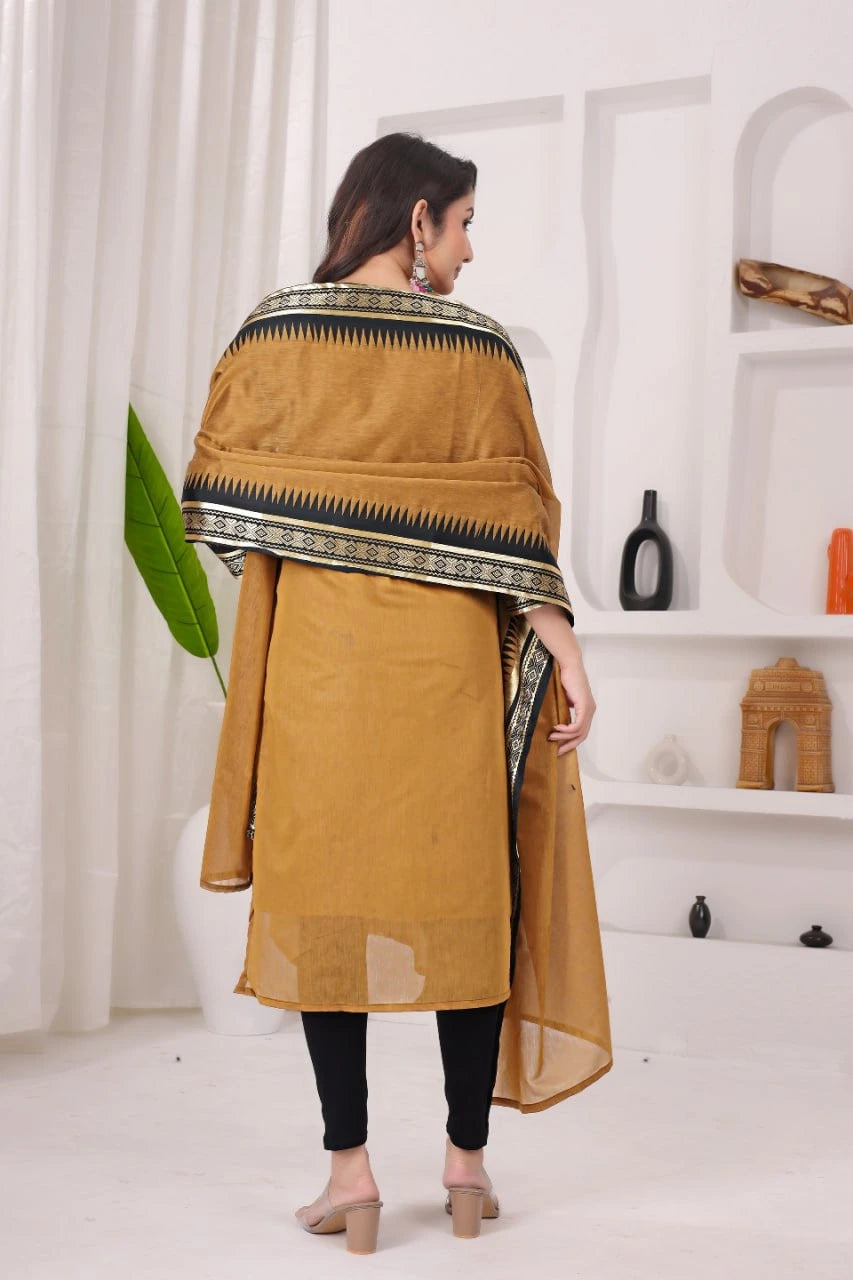 Woman wearing a mustard yellow kurta with a patterned shawl in a minimalistic room.