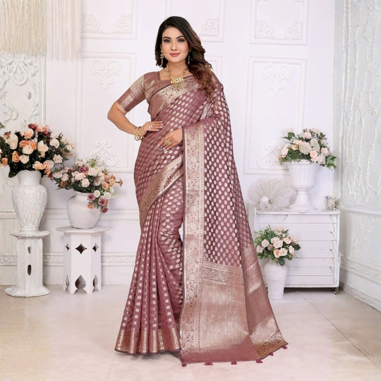 Woman wearing a traditional saree in a decorated room with flowers and vases.