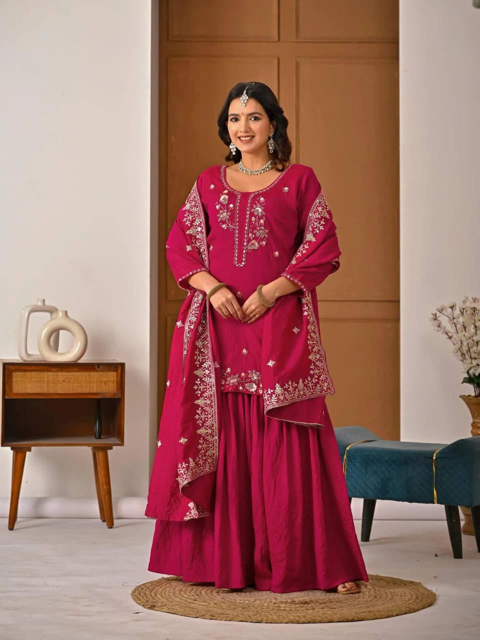 Luxurious crimson red embroidered suit folded neatly, showcasing fine zari weaving details.