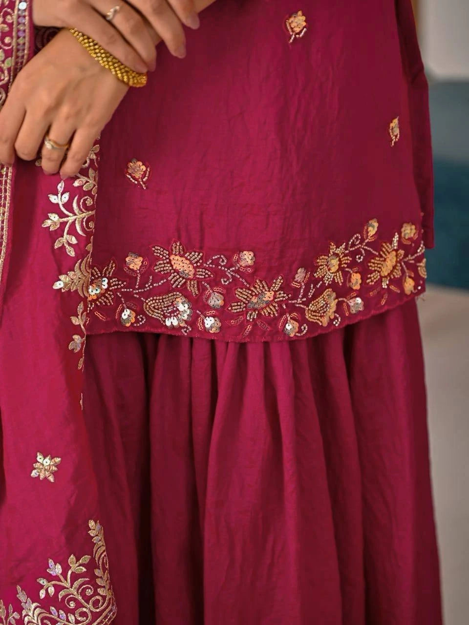 Crimson red embroidered suit displayed with elegant dupatta featuring zari detailing.