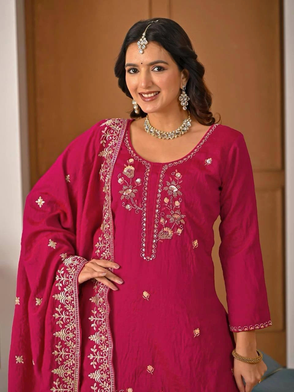 Full-length crimson red embroidered suit styled with matching dupatta and pants.