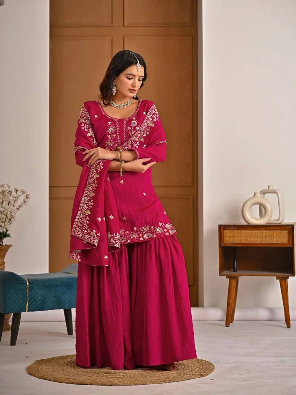 Close-up of crimson red georgette fabric highlighting detailed embroidery and zari craftsmanship.