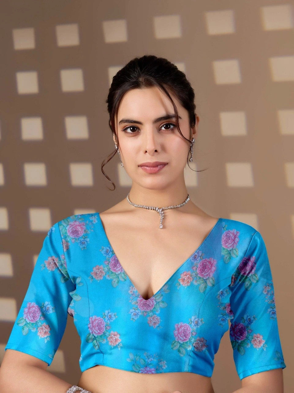 Woman wearing a blue floral blouse against a checkered wall.