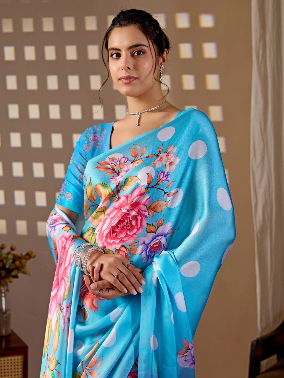 Woman wearing a blue saree with floral patterns against a neutral background