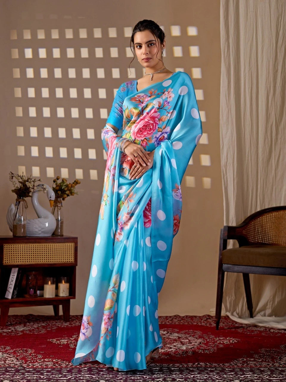Woman wearing a blue saree with floral patterns in a room setting.