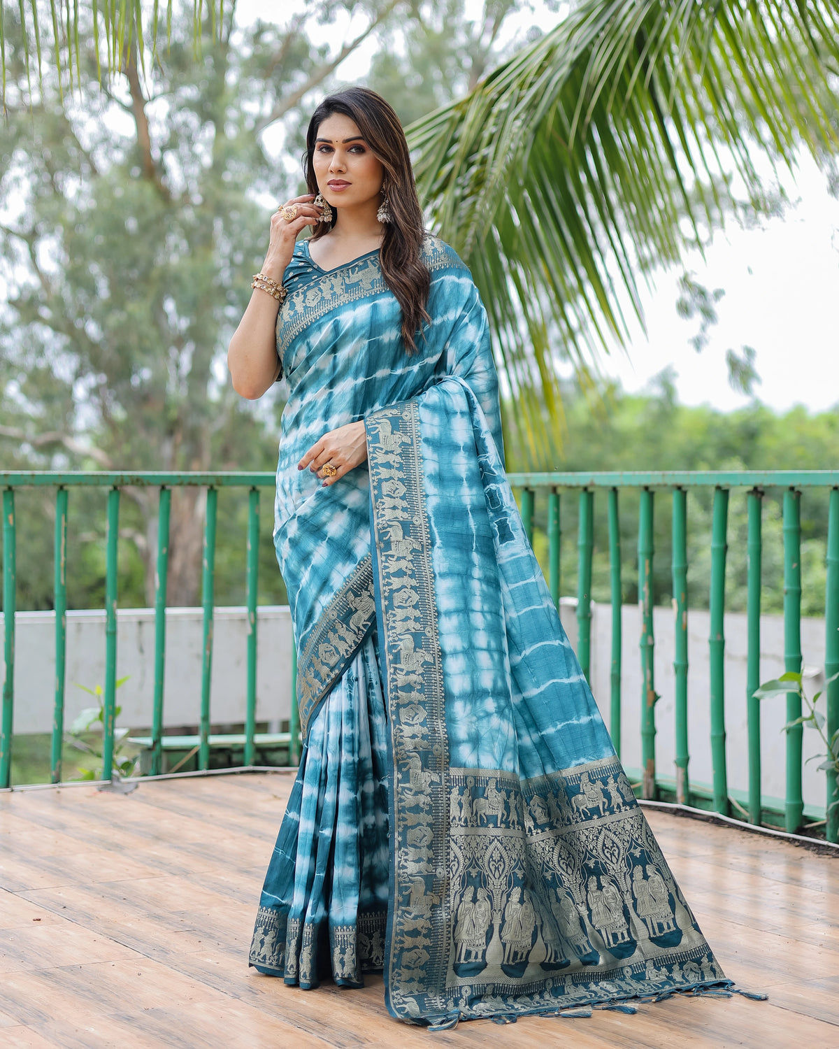 Woman wearing a blue and green saree with a scenic background