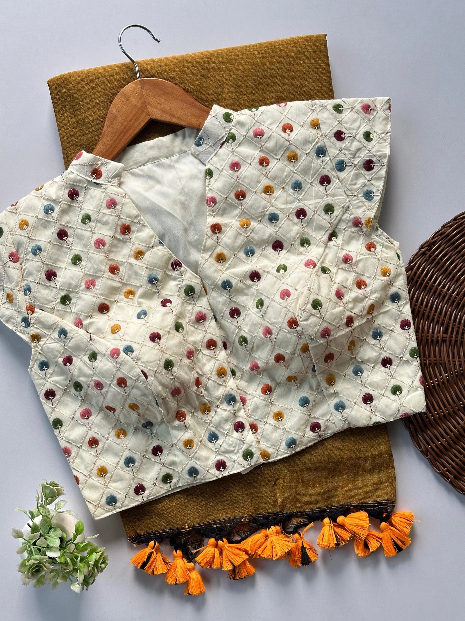Textile with colorful polka dots and orange tassels on a wooden hanger against a neutral background