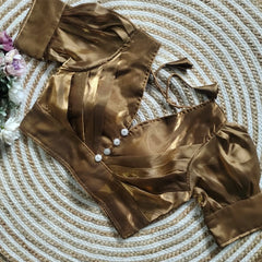 Dark Brown blouse with pleated detailing and three decorative silver buttons on the front, featuring elbow-length sleeves and tie-up tassels, displayed on a circular woven mat with white and pink flowers on the side.