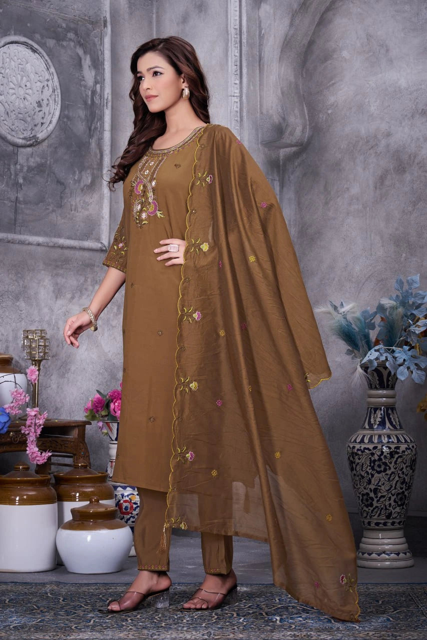 Woman wearing a brown embroidered outfit with a gray textured wall background